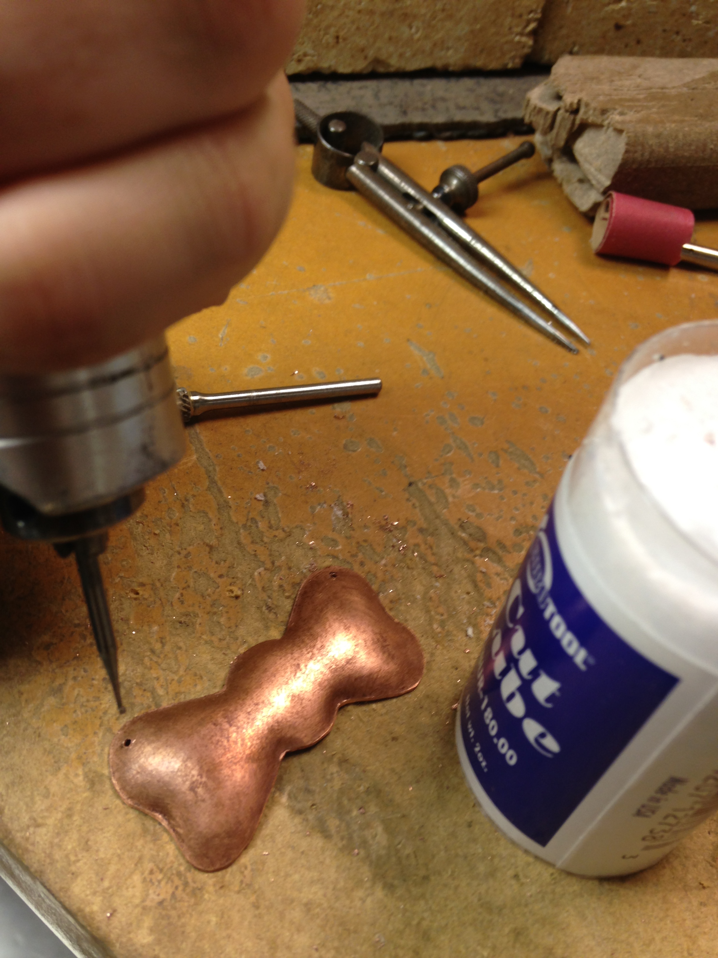 hand held drill with lubrecant to drill holes in metal piece