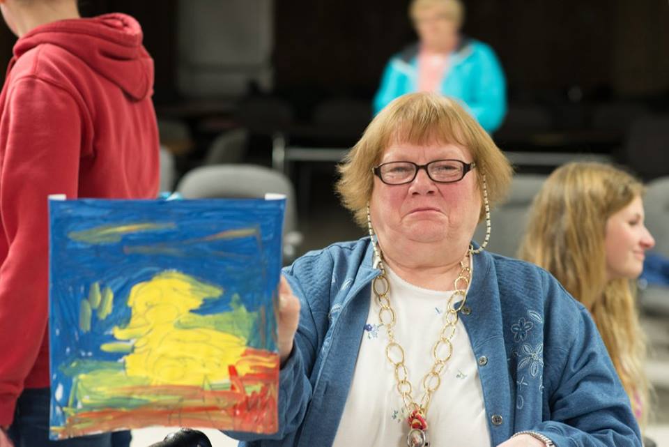 elderly woman holding up her painting