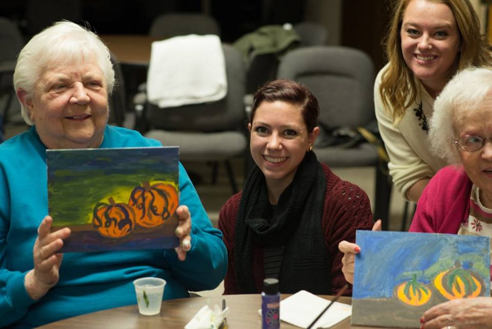 senior citezens with young people and pumpkin paintings