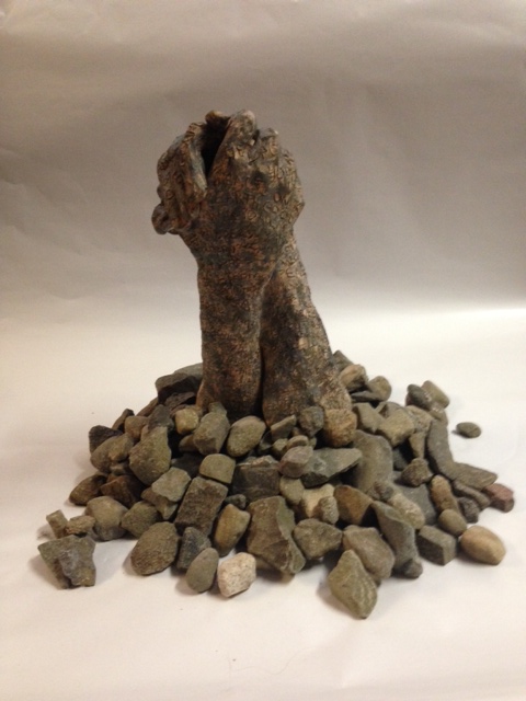 two embracing clay hands appearing like rocks with rocks placed around them