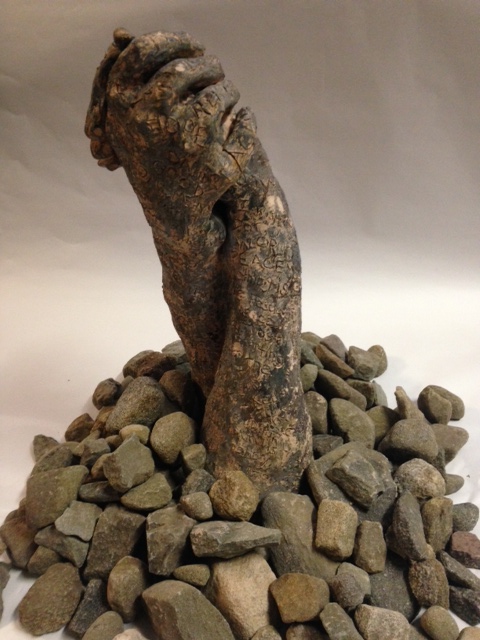 two embracing clay hands appearing like rocks with rocks placed around them