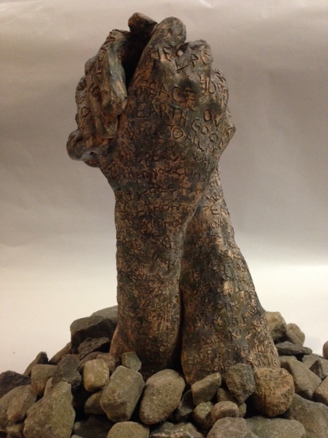 two embracing clay hands appearing like rocks with rocks placed around them