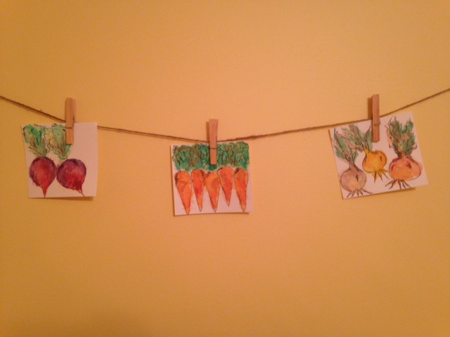 hanging watercolor pictures of radishes, carrots, and onions