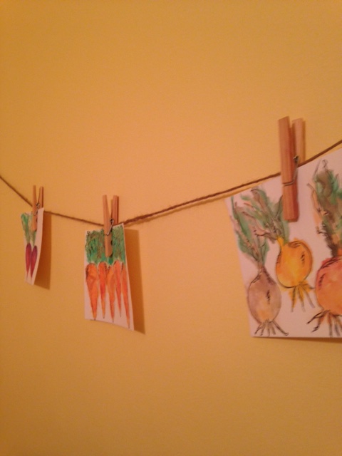 hanging watercolor pictures of radishes, carrots, and onions