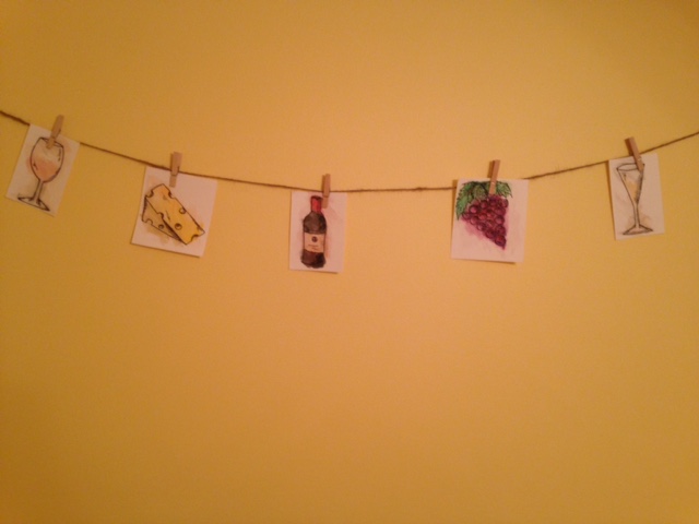 hanging watercolor pictures of wine glasses, cheese, wine bottle, and grapes