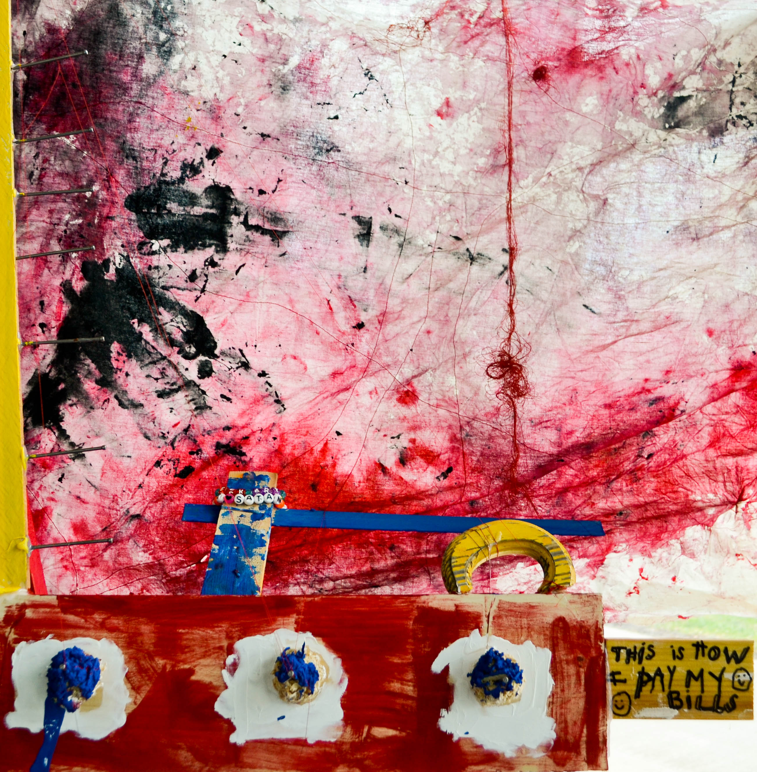 red, blue, yellow installation art that says "this is how I pay my bills"