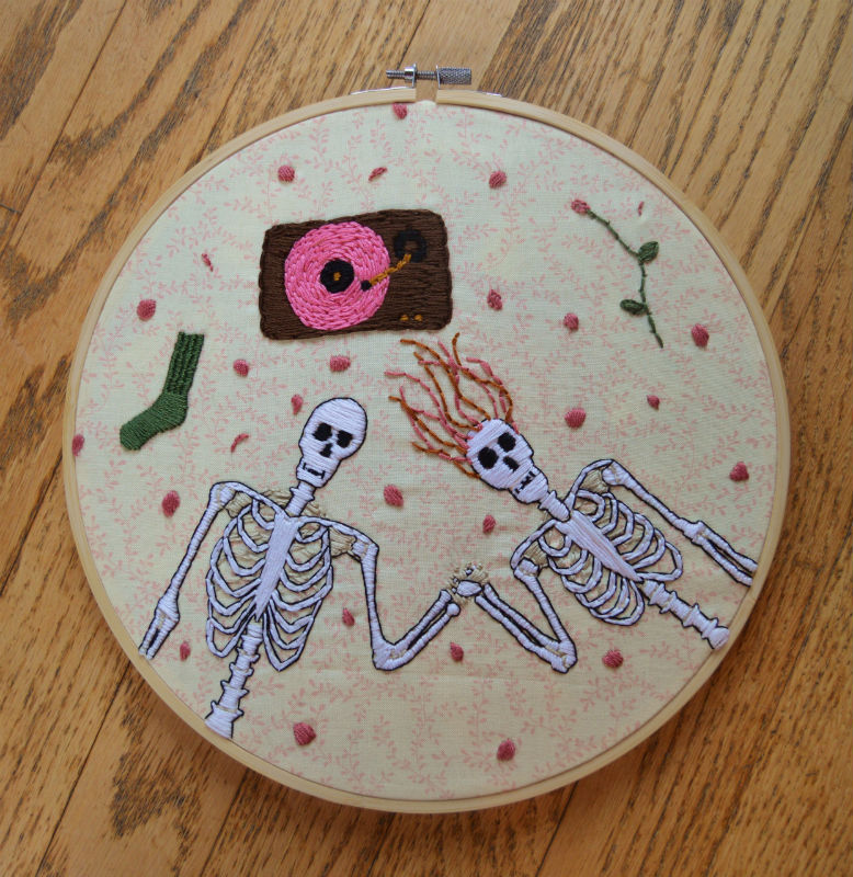 Embroidered skeleton couple with black outline lying on the floor listening to pink vinyl record