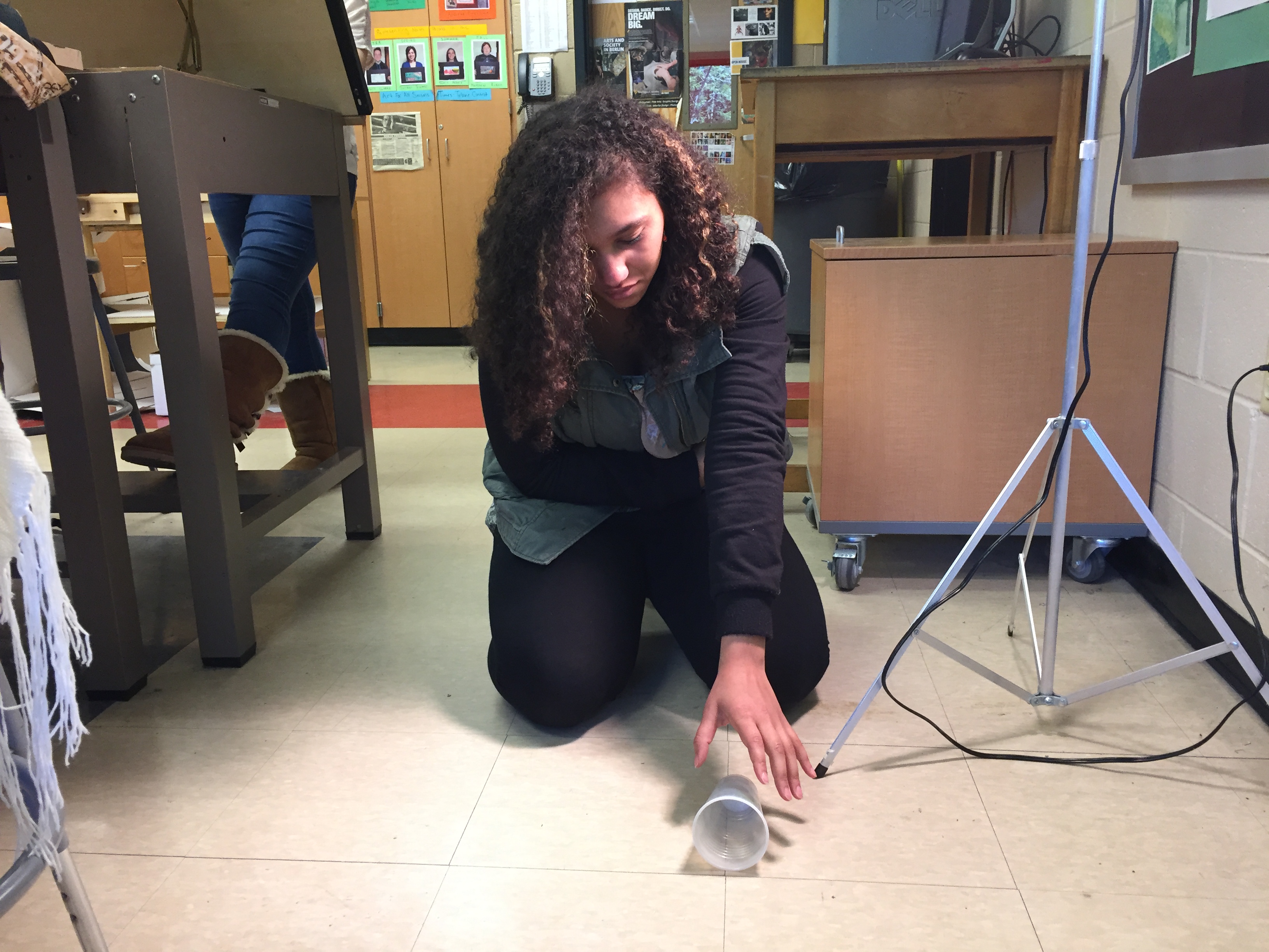 Girl kneeling on floor reaching for cup with dramatic lighting