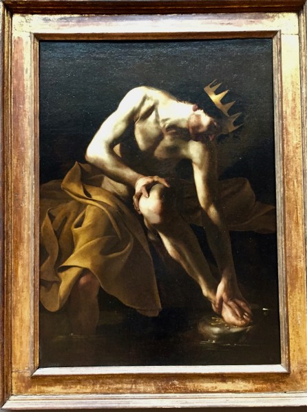 Man with crown and blanket washing feet in a river