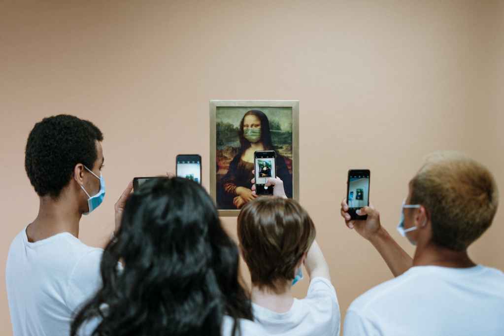 people taking picture of a painting of mona lisa with face mask