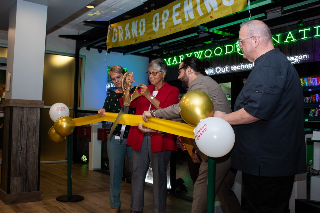 Four people cutting a "Grand-Opening" ribbon enthusiastically
