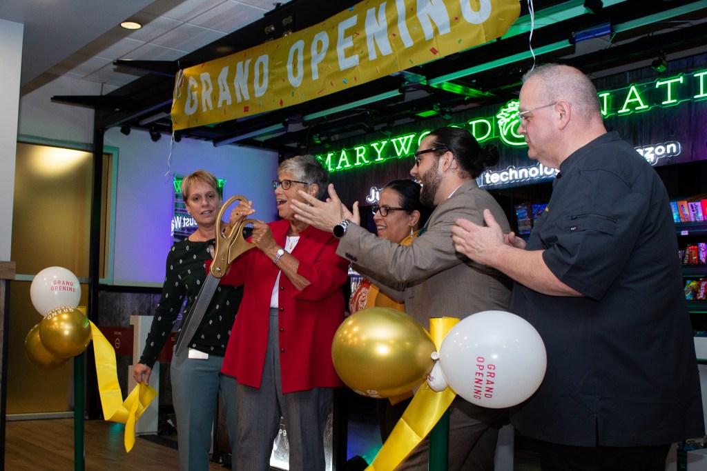 Four people cutting a "Grand-Opening" ribbon enthusiastically