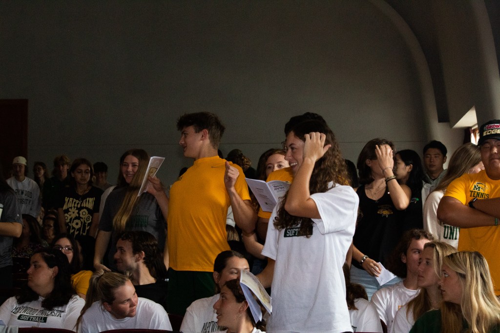 Students standing, reading from a pamphlet