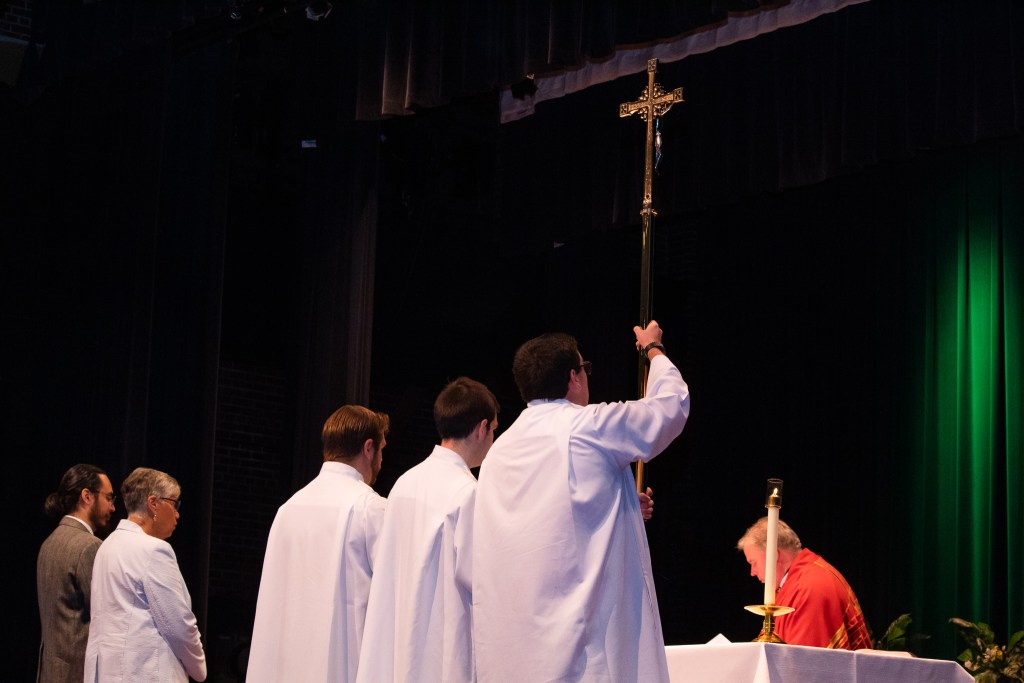 Three men holding up a cross
