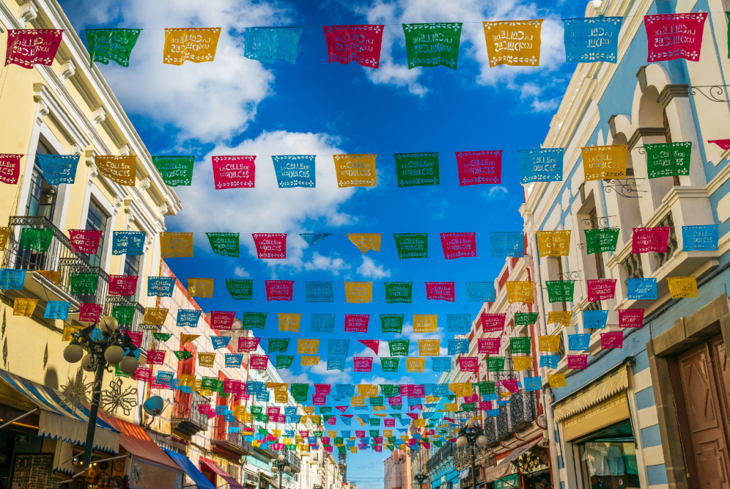 Image of Papel Picado. Colorful perforated paper strung between buildings.